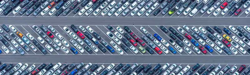 Aerial view of a car yard with hundreds of cars parked in rows.